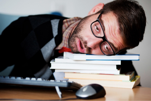 Мужчина лежит на учебниках